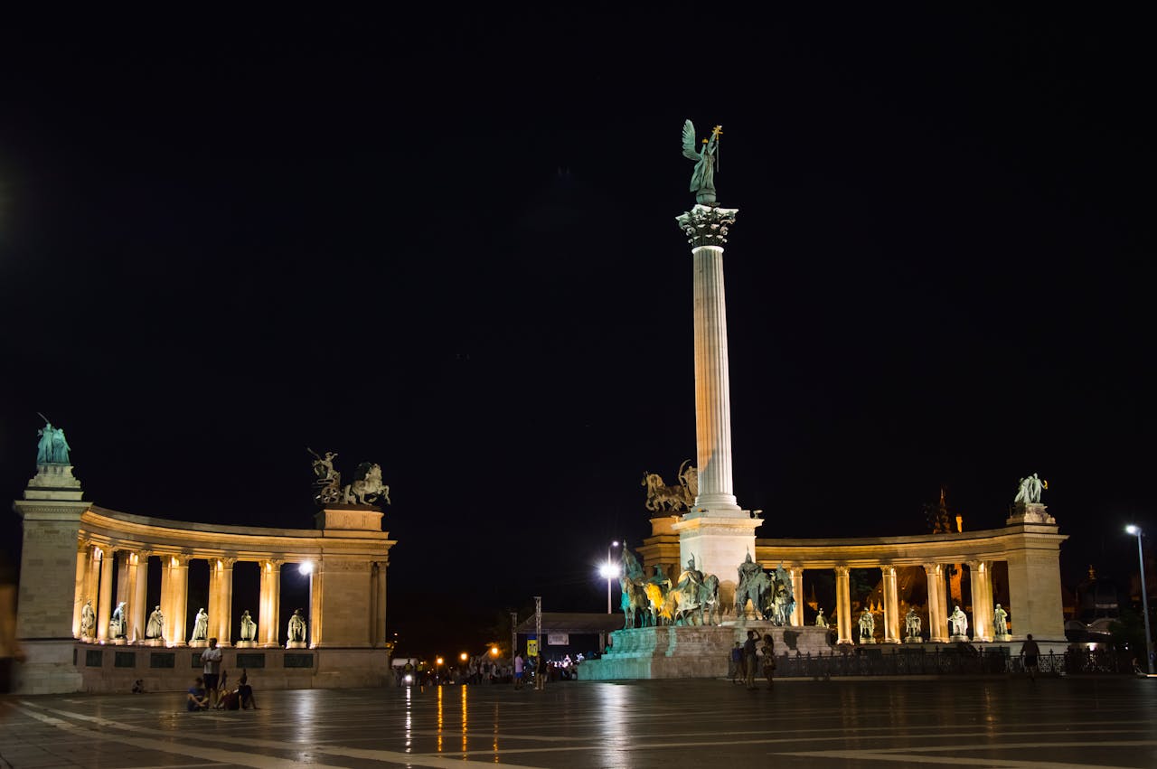 The iconic Heroes' Square illuminated at night, showcasing the elegance of exploring the city with the Hummer Limousine XL in Budapest.