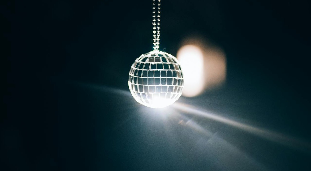 A sparkling disco ball radiates light, creating a vibrant party atmosphere, reminiscent of the luxurious lighting setup inside the Cadillac Limousine Budapest.