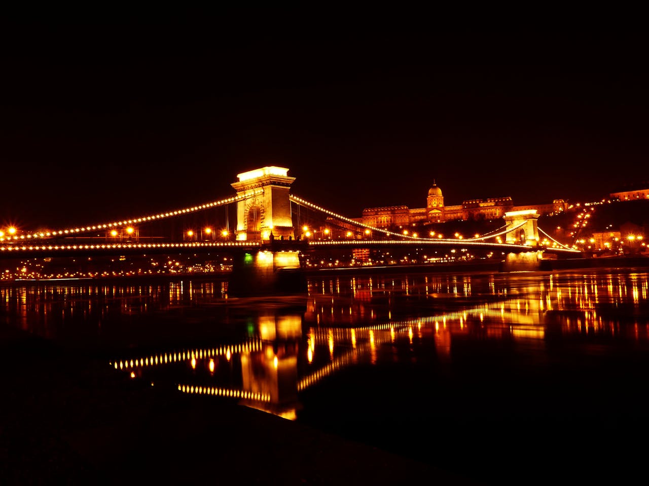 A breathtaking nighttime view of Budapest's Chain Bridge and Buda Castle, perfect for a luxurious ride in a Lincoln Navigator Limousine Budapest, enhancing the elegance of the city's iconic landmarks.