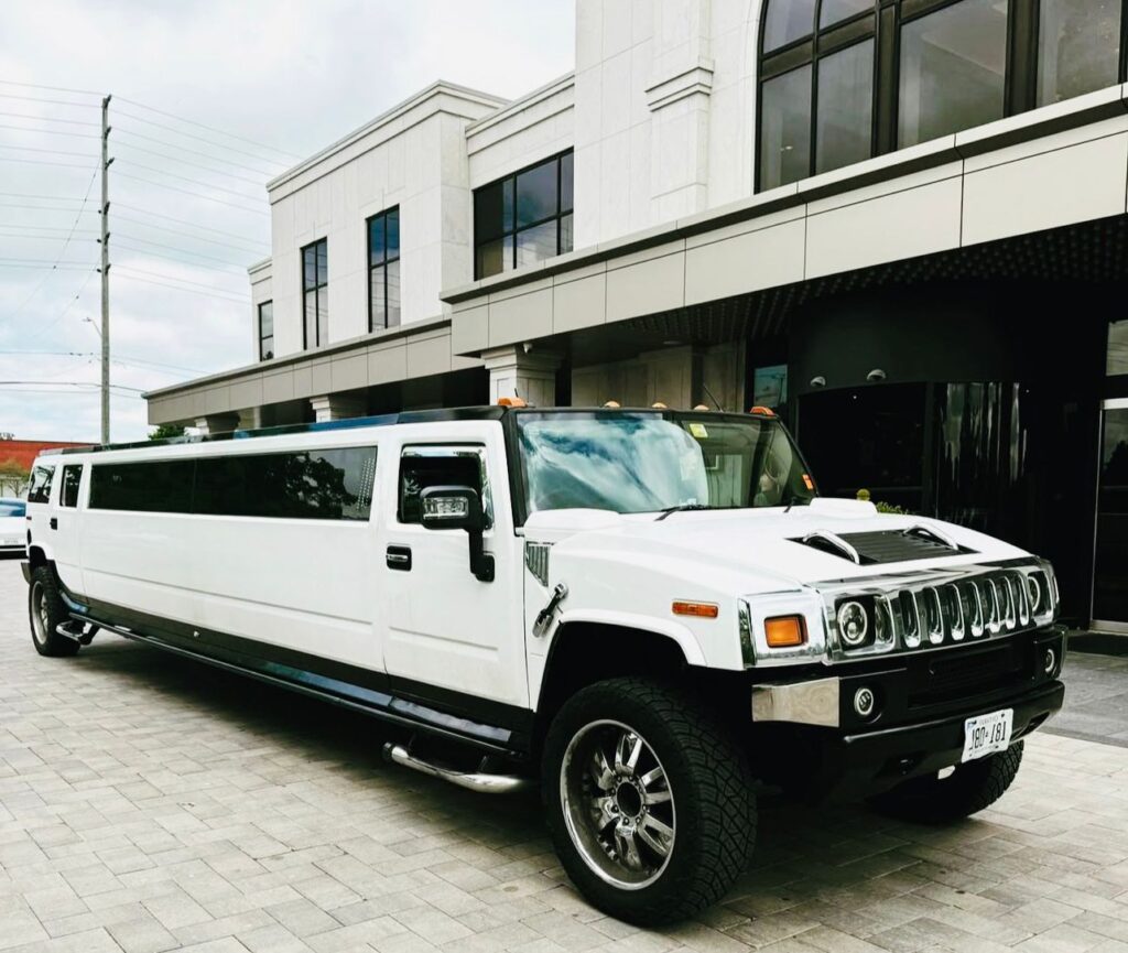 White Hummer limousine in Budapest parked in front of a modern building, symbolizing luxury limo rental and VIP experience.