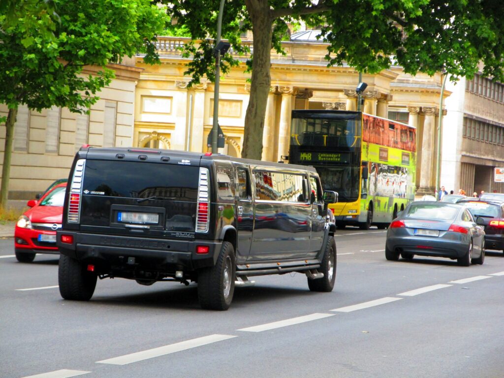 “Black Hummer limousine driving in the city, ideal for medium-sized groups of 12 to 20 passengers in Budapest.