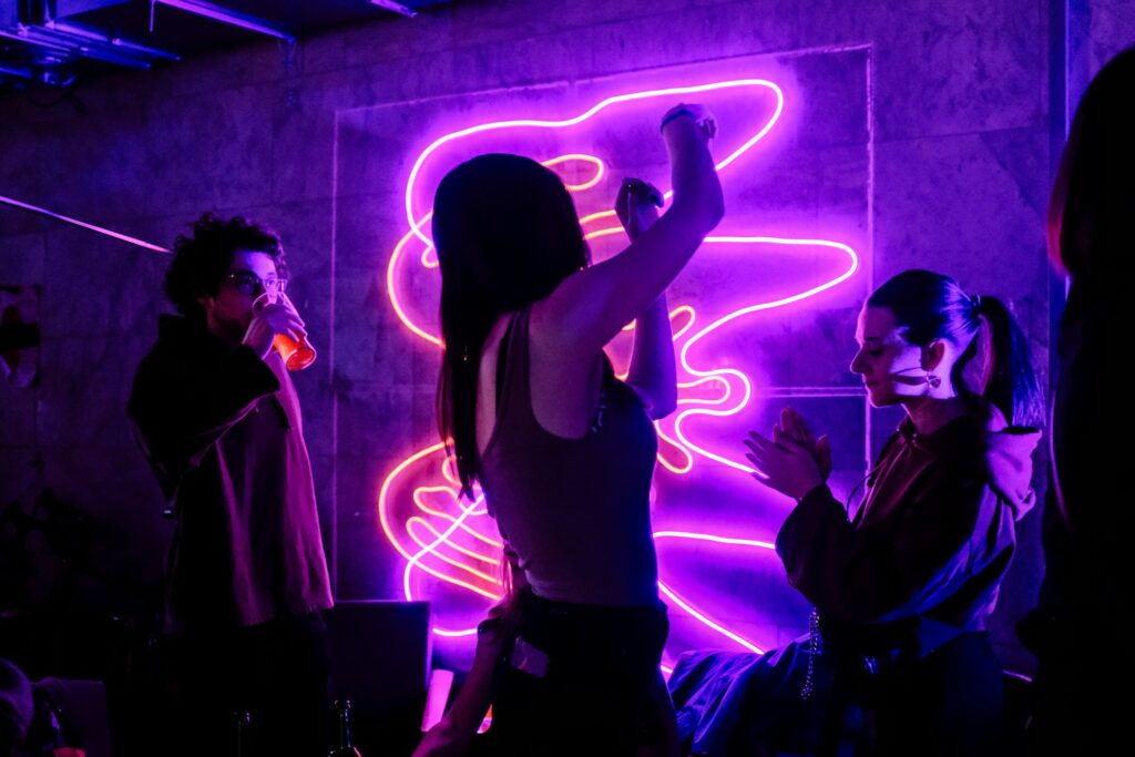 Young people partying under neon lights in Budapest, symbolizing the energetic atmosphere of a party bus compared to a Hummer limo.