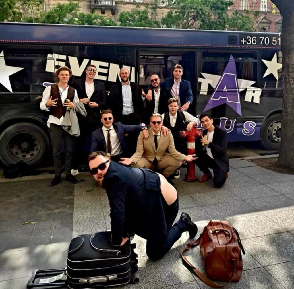 Stag group posing in front of a party bus in Budapest, highlighting the choice between party bus vs Hummer limo Budapest for group celebrations.