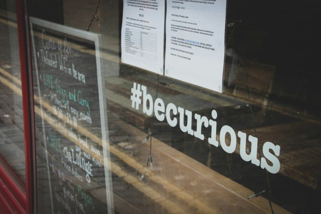 Window sign with hashtag #becurious, symbolizing frequently asked questions about limo rental in Budapest.