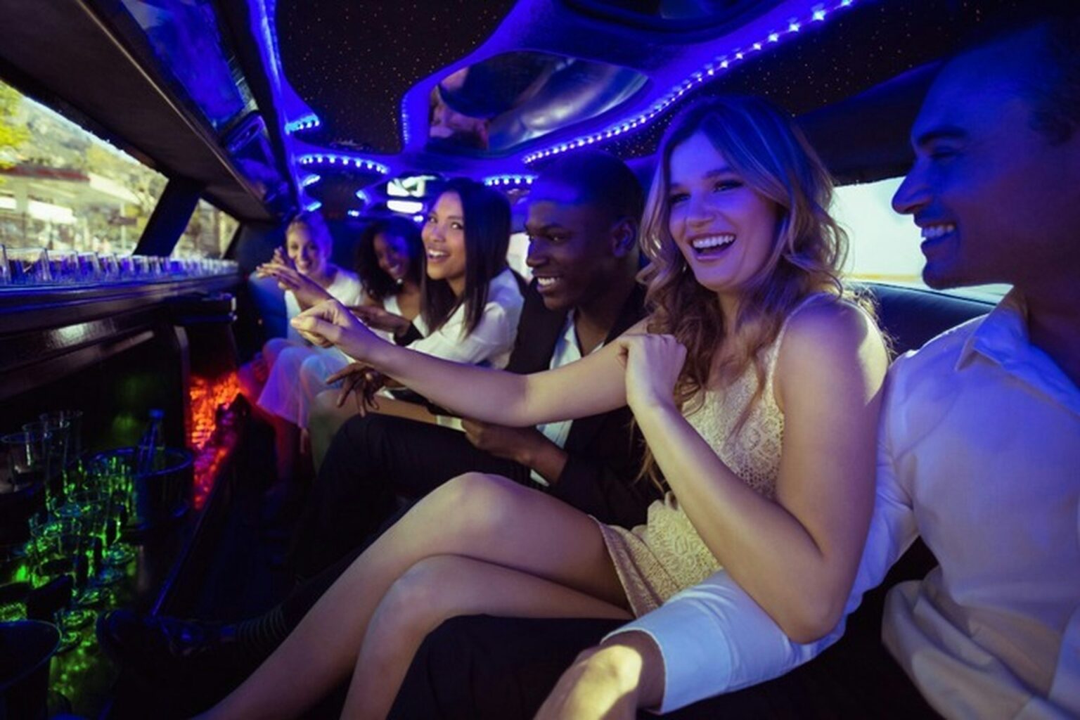 Friends enjoying a night out in a party limousine in Budapest with colorful LED lights and drinks on board.