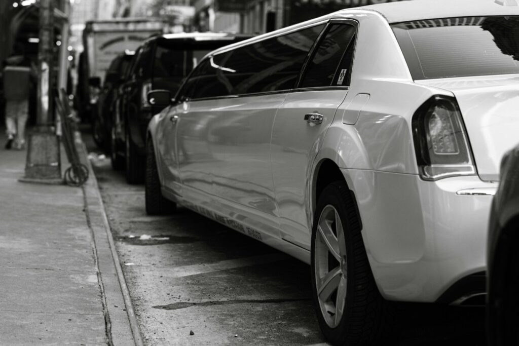 A white stretch limousine parked on a city street, representing the elegance and comfort of airport limousine rental Budapest services for luxury airport transfers.
